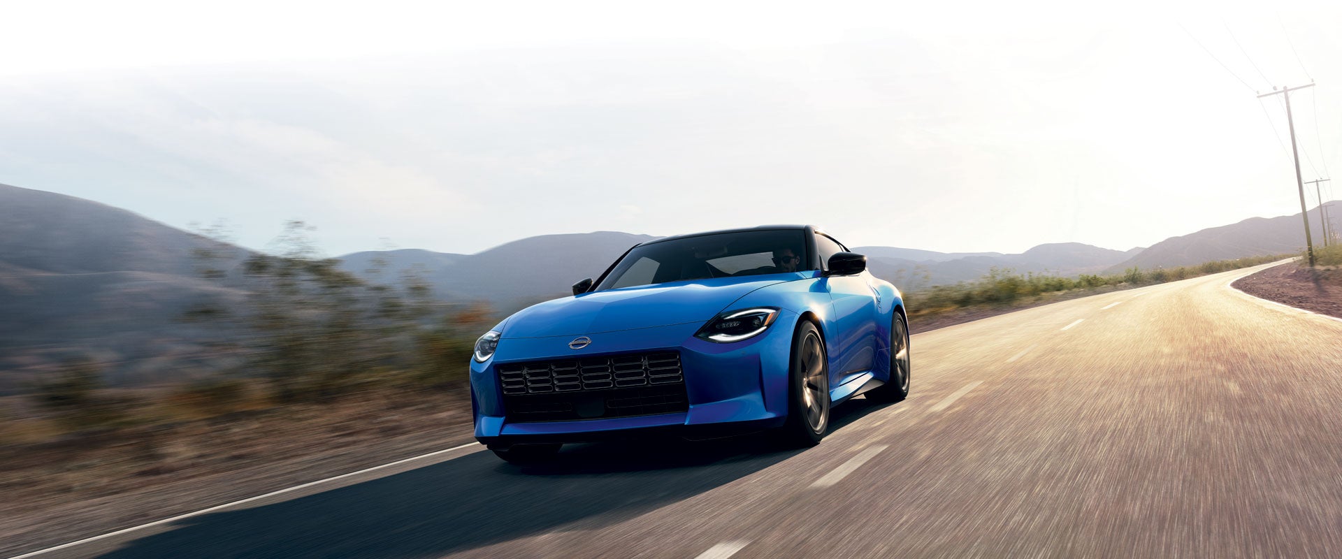 2024 Nissan Z in blue driving on a rural road at speed